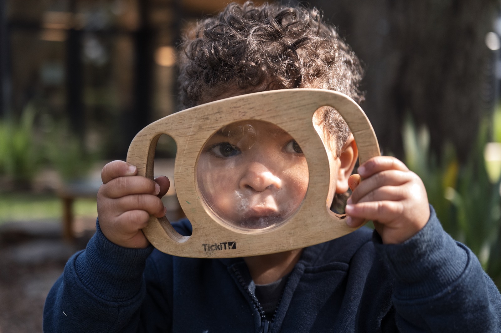 A child exploring through a wooden magnifier at a Bear Park centre