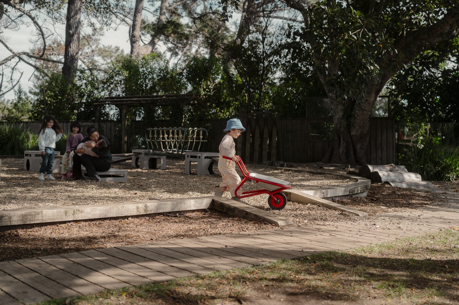 A teacher cradling a baby in the garden at Bear Park Hobsonville